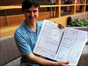 Composer Julian Darius Revie at Saint Thomas More Chapel at Yale University, with the score of Mass of the Divine Shepherd.